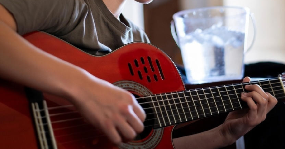 Guitarist practicing chord shapes on an acoustic guitar neck